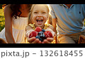 children and parents sharing fresh berries outdoors, candid family moment during sunny berry picnic in park, happy family enjoying carefree summer afternoon with fresh mixed berries outdoors 132618455