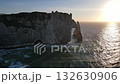 Iconic chalk cliffs and turquoise waters of Etretat glow under sunlight, showcasing Normandy's natural beauty and peaceful coastline. 132630906