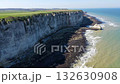 Iconic chalk cliffs and turquoise waters of Etretat glow under sunlight, showcasing Normandy's natural beauty and peaceful coastline. 132630908