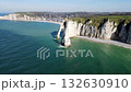 Iconic chalk cliffs and turquoise waters of Etretat glow under sunlight, showcasing Normandy's natural beauty and peaceful coastline. 132630910