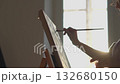An artist in silhouette paints on an easel, illuminated by warm sunlight, embodying creativity and inspiration in a serene, sunlit environment that invigorates the artistic spirit 132680150