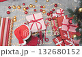 In a warm, joyful atmosphere, a cheerful person wraps colorful Christmas presents, surrounded by shiny ornaments and vibrant decor, capturing the essence of the festive holiday season 132680152