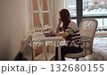 In a stylish white room, a young woman sits at her modern desk, immersed in her advanced laptop, showcasing concentration, creativity, and the essence of modern workspaces to inspire others 132680155