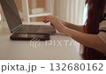 In a beautifully organized workspace, a focused woman types away on her sleek and sophisticated laptop, seamlessly blending modern technology with her effective and productive work habits 132680162