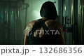 dedicated female athlete focuses on form while performing a cable rope row to strengthen her back and arms in a gym environment. This intense workout showcases her determination and commitment. 132686356