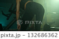 female athlete grips a barbell with intent executing deadlifts in a gym setting. The atmosphere is intense with dramatic lighting emphasizing her strength and focus during the workout. 132686362