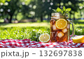 refreshing iced lemon and honey tea in glass jar with mint in sunny park setting on meadow during picnic, condensate drops on mug or cup 4k 132697838