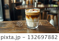 creamy iced coffee drink served in clear glass, cappuccino or latte with foam, layers and caramel topping in cozy cafe setting 4k 132697882
