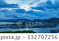 Time lapse A vibrant sunset illuminates a serene Phuket fishing harbor, with colorful boats docked along calm waters and dramatic clouds painting the sky in hues of orange, pink, and blue. 132707256
