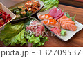 Sushi platter with vibrant rolls, sashimi, and garnishes on a wooden table in a cozy setting 132709537