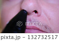Close-up macro footage of a man using an electric trimmer to remove nose hair. 132732517