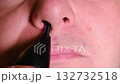 Close-up macro video of a man using an electric trimmer to remove nose hair, focusing on personal grooming 132732518