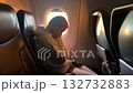 Calm passenger by window seat, passenger relaxes with cozy attire during smooth flight descent 132732883