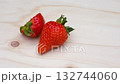 4K video of half a strawberry and a whole strawberry slowly rotating on a wooden board 132744060