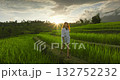 Woman enjoying peaceful sunset stroll on pathways of lush green rice terraces on Bali island, experiencing nature and serenity during a travel adventure in Indonesia. Beautiful tropical vacation Woman enjoying peaceful sunset stroll on pathways of lush green rice terraces on Bali island, experiencing nature and serenity during a travel adventure in Indonesia. Beautiful tropical vacation 132752232