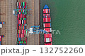 Cargo ship docks at a busy industrial port, having colorful shipping containers loaded and unloaded by cranes, representing global logistics and transportation. Top down aerial drone flight Cargo ship docks at a busy industrial port, having colorful shipping containers loaded and unloaded by cranes, representing global logistics and transportation. Top down aerial drone flight 132752260