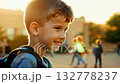 Close up view of a Caucasian pupil boy with backpack standing next the school. Smiling Caucasian boy stands proudly by school, ready for a day of learning. 132778237