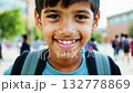 Close up view of a Caucasian pupil boy with backpack standing next the school. Close-up of smiling Caucasian boy with backpack standing confidently by school. 132778869
