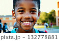 Close up view of an African American pupil boy with backpack standing next the school. Close-up of smiling schoolboy with backpack standing proudly by the school. 132778881