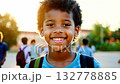 Close up view of an African American pupil boy with backpack standing next the school. Smiling boy with backpack stands near school, hopeful and ready for learning. 132778885