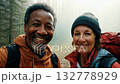 A middle aged couple of hikers in a mountain forest looking at camera and smiling. Middle-aged duo beams at camera amid towering trees on a peaceful mountain trail. 132778929