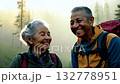 A middle aged couple of hikers in a mountain forest looking at camera and smiling. Joyful hikers look at the camera, soaking in the tranquility of the forested mountain landscape. 132778951
