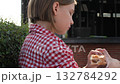 Preteen Girl Eating Burger Outdoors in Plaid Shirt 132784292