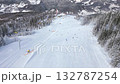 Aerial view of snowy ski slope with people skiing and chairlifts in winter mountain resort. Perfect for themes of travel, tourism, winter sports, lifestyle, and holiday adventure. 132787254