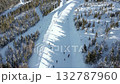 Aerial view of snowy ski slope with people skiing and chairlifts in winter mountain resort. Perfect for themes of travel, tourism, winter sports, lifestyle, and holiday adventure. 132787960