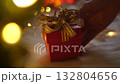Hand woman putting red gift box on white wool with bokeh lights in christmas time 132804656