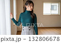 A woman in a turtleneck stands by the window of her new home and looks outside 132806678
