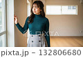 A woman in a turtleneck standing by the window in an empty room and looking outside 132806680