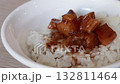 Stirring and pouring braised pork belly meat over cooked rice. 132811464