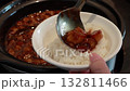 Stirring and pouring braised pork belly meat over cooked rice. 132811466