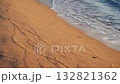 Sandy beach with gentle waves lapping at the shore. The sand has visible patterns and textures created by the water. 132821362