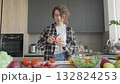 Young Woman Peeling Tomato For Salad Preparation In Bright Stylish Kitchen 132824253