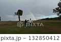 Loving couple holds hands and sprints across field, double rainbow shining ahead, scene conveys affection, freedom, and pursuit of dreams side by side. 132850412