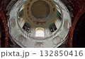 Upward interior view of abandoned church dome reveals birds flying near open windows, flapping wings and silhouettes animate quiet space, highlighting new life within decaying sacred walls. 132850416