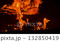 Macro shot captures vibrant flames leaping from burning wood in metal grill, intense heat and glowing orange light evoke warmth and atmosphere of outdoor barbecue. 132850419