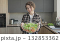 Smiling Woman Holding Fresh Vegetable Salad Bowl In Modern Kitchen 132853362