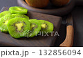 Sweet creamy delight freshly cut kiwi slices on black cutting board. 132856094
