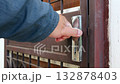 A person in a blue jacket unlocking a strong brown metal door with secure locking mechanism and grid pattern for safety and durability 132878403