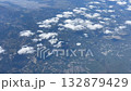 Aerial view of fluffy clouds floating over a beautiful cityscape surrounded by nature 132879429