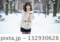 A smiling woman playing in the snow in a knitted sweater and skirt in a snowy park 132930628