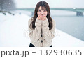 A woman wearing a knitted sweater blows on her hands in a snowy landscape 132930635