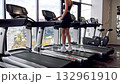 Sofia, Bulgaria - 11.10.2025. Young woman preparing for workout in modern gym, adjusting settings on treadmill before running. Large panoramic windows overlook the city buildings, creating an urban 132961910