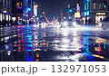 Urban street scene at night with vibrant reflections of city lights and neon signs on the wet asphalt, creating a dynamic mosaic of colors and movement with passing vehicles and pedestrians 132971053