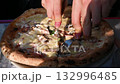 Naples, Italy, December 30, 2024. The city's iconic food: an inviting, freshly baked pizza being cut in half. Warm winter light, close-up of the pizza. 132996485