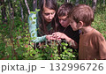 Mother and children observing insects in the forest 132996726