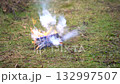Burning e-bike batteries on grass emit thick smoke and bright flames, bursting and exploding in a dangerous outdoor fire scene 132997507